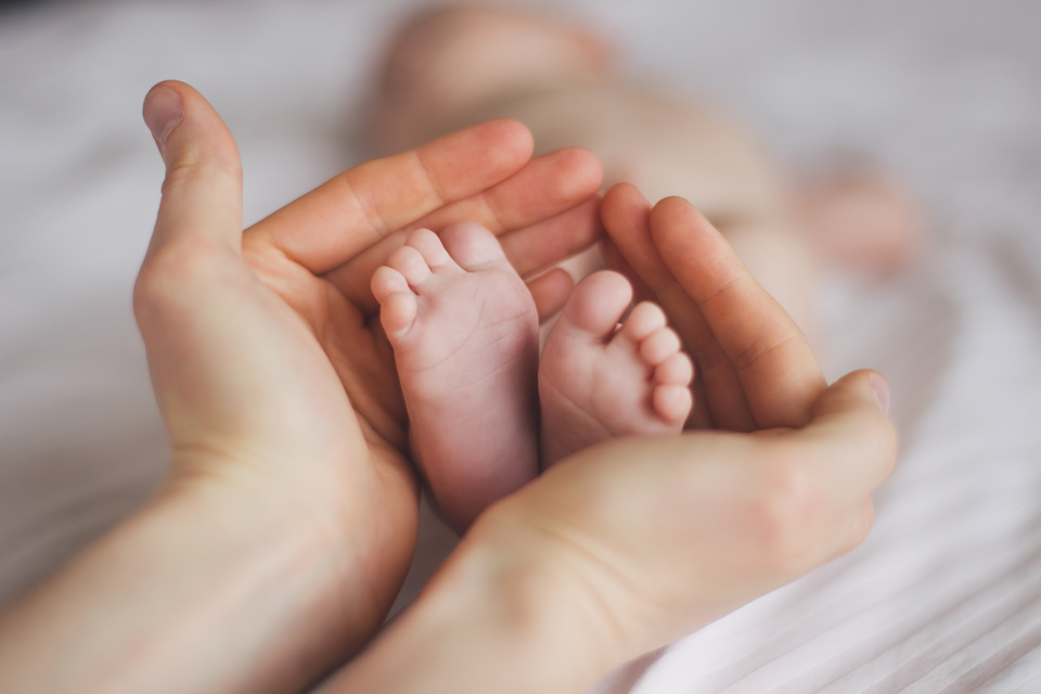 Hands cupping new-born babies feet